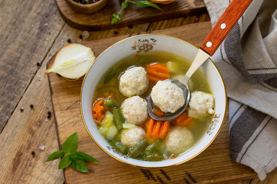 The concept Diet menu. Healthy soup with vegetables and chicken meatballs in a bowl on wooden table in rustic style.