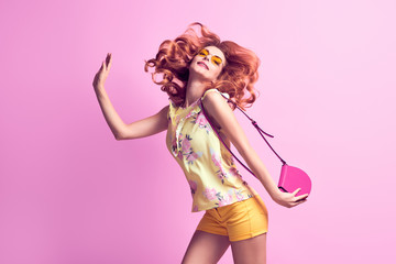 Girl jumping fooling around in studio. Young beautiful pretty woman having fun laughing dance in Fashion Stylish outfit, makeup. Cheerful redhead model on purple