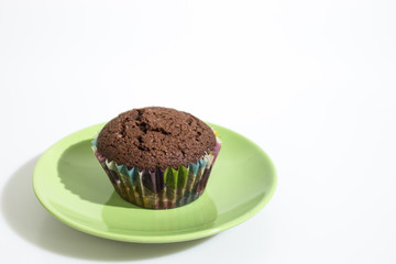 Chocolate cupcake on a green plate isolated in a white background