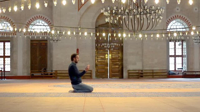 Young muslim praying inside of a mosque