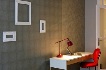 Modern apartment with computer desk, laptop, red chair and lamp