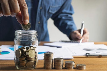 Fototapeta premium Business man putting the money in glass jar to saving,financial,accounting concept.