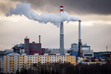 Stream of dark smoke from the chimney of factory in the industrial district