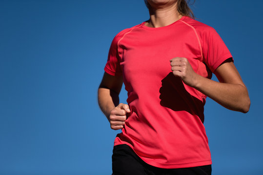 Athlete woman running in red t-shirt and on blue sky background