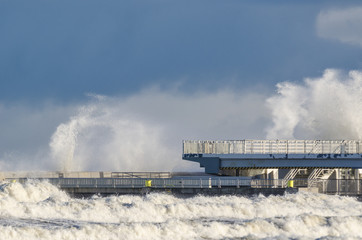 Fototapeta na wymiar STORM AT SEA - Waves attack the sea coast and pier in Kolobrzeg 