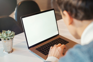 Young man working in front of the laptop with blank white screen.