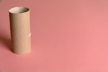 A blank paper toilet roll on a pink background.
