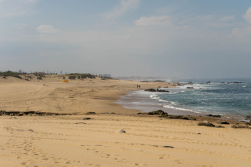Ocean beach in Madalena, near Porto, Portugal. Yellow sand and lots of big rocks, big waves on atlantic ocean.