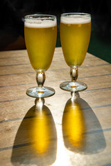 Two cold light unfiltered beer in glasses served on sunny outdoor terrace in garden