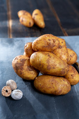 New harvest potatoes not washed with soil on table with nutmeg