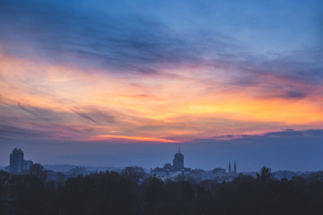 Fototapeta premium Dim winter twilight. Clouds at sunset over dark industrial town.