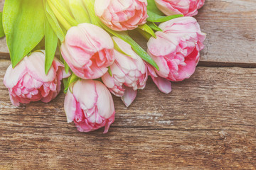 Obraz na płótnie Canvas Spring greeting card. Bouquet of fresh light pastel pink tulips flowers on wooden background. Happy holiday easter mother day anniversary valentine day birthday concept. Flat lay top view copy space