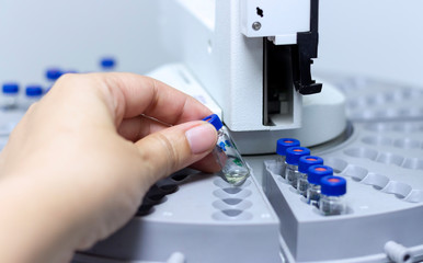 Scientist holds a chemical sample vial. People hand holding a test tube vial sets for analysis.laboratory assistant inserting laboratory glass bottle in a chromatography vial.