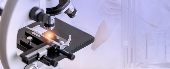 Close-up shot of microscope with laboratory equipment background