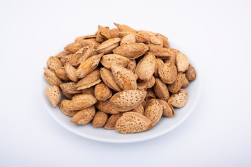 Almond nuts in shells and they are in white porcelain bowl