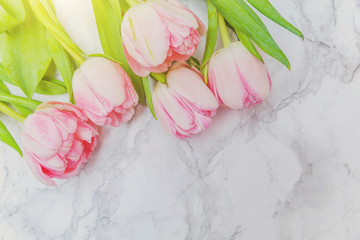 Obraz na płótnie Canvas Spring greeting card. Bouquet of fresh light pastel pink tulips flowers on marble background. Happy holiday easter mother day anniversary valentine day birthday concept. Flat lay top view copy space
