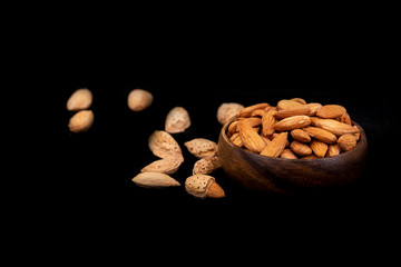 Raw almonds with shell, almond nuts in the wooden plate