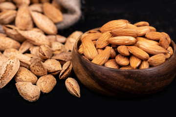 Raw Almonds nuts on wooden plate and almonds with shell