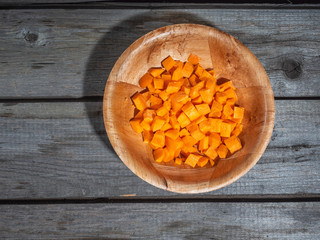 Raw carrot, diced in a deep plate. Shot from above on a wooden old table. Close-up.