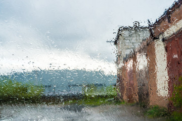 Rainy impressionism, cozy city silhouettes view through wet glass window with raindrops, concept of...