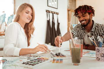 Fototapeta premium Loving handsome boyfriend joining his appealing girlfriend drawing