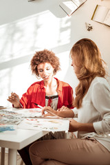 Two stylish appealing women speaking while drawing together