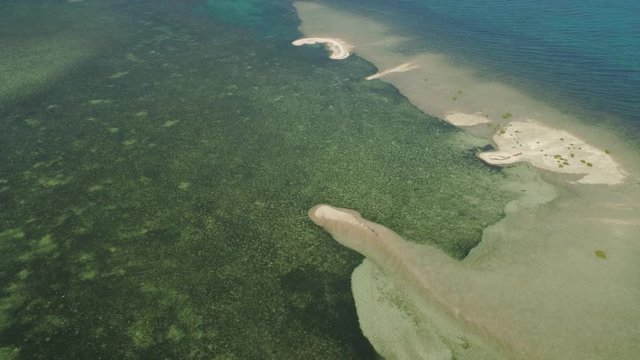 Small sandy island in sea. Tropical island with white sandy beach. Aerial view sandy Cory island with colorful reef. Seascape, ocean and beautiful beach. Philippines, Anda, Pangasinan. Travel concept.