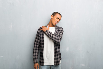 Young african american man with checkered shirt suffering from pain in shoulder for having made an effort