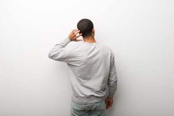 African american man on white wall background on back position looking back while scratching head