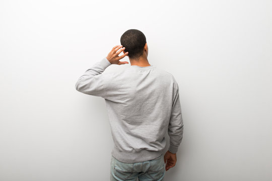 African American Man On White Wall Background On Back Position Looking Back While Scratching Head