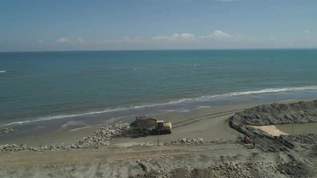 Construction coastal protective structures, protect against sea waves on Lingayen Beach. Aerial view construction equipment at sea, beach facilities, construction of quay. Philippines, Luzon