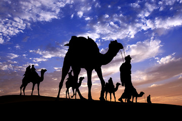 Fototapeta na wymiar Caravan Walking with camel through Thar Desert in India, Show silhouette and dramatic sky