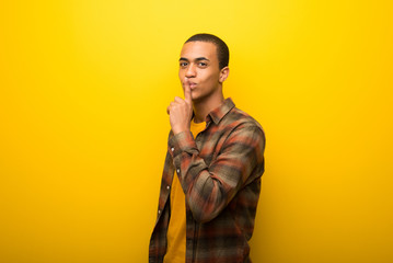 Fototapeta premium Young african american man on vibrant yellow background showing a sign of closing mouth and silence gesture