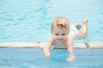 Fototapeta na wymiar Portrait of a happy baby girl in the swimming pool 