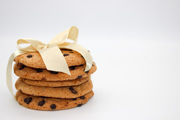 Oatmeal cookies with chocolate drops, tied with a golden ribbon, isolated on white background