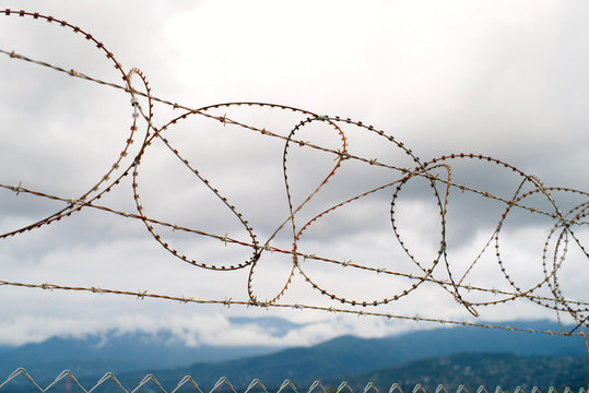 Barbed wire against the background of the cloudy sky and mountains