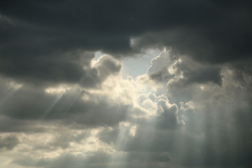 Fototapeta premium The sun's rays breaking through the dark rain clouds