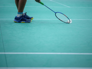 Indoor badminton court with the player leg , shuttle cock and the racquet, selective focus