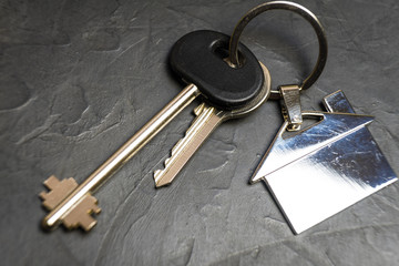 keys to the house with a keychain in the shape of the house.