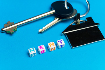 Inscription rent written colored cubes. Photo on the background of a key FOB in the shape of a house.