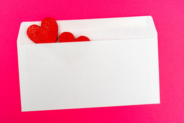 Two red hearts in a white envelope.