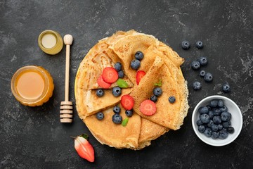 Crepes or blini with berries and honey. Maslenitsa food. Table top view