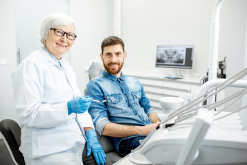 Obraz premium Portrait of a handsome male patient in blue shirt with elderly woman dentist in the dental office