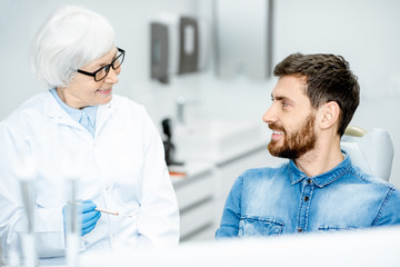 Obraz premium Handsome man during the dental consultation with elderly woman dentist in the dental office