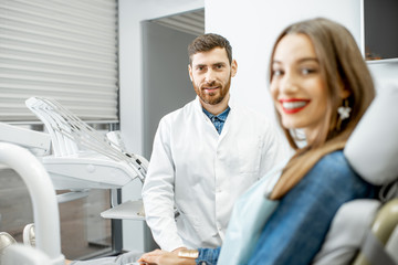 Portrait of a handsome dentist with woman patient in the dental office