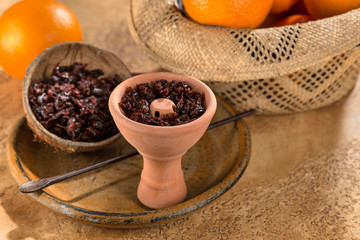 Hookah in a clay bowl for Smoking hookah with persimmon fruit in the background.