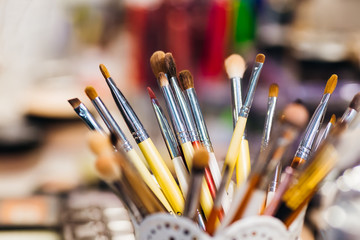 many cosmetic brushes of different shapes in the stand