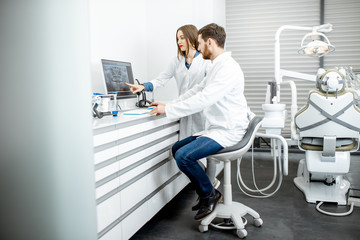 Dentist with young woman assistant working with computer in the dental office