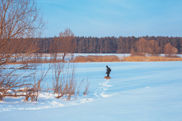 Man walking with dog on the frozen lake back to camera