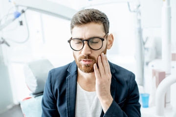 Businessman having a toothache waiting for the doctor in the dental office